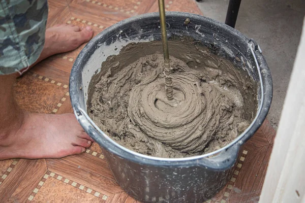 混合水泥胶粘剂与搅拌机在桶内的特写 混合砂浆的质地 免版税图库照片