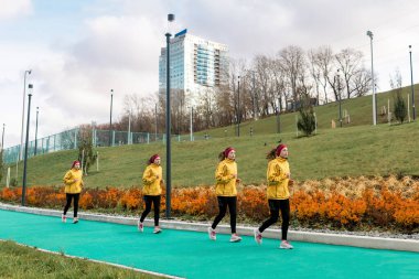 Aynı kadın koşucunun şehir arka planına karşı koşu pistinde birden fazla görüntüsü olan panorama