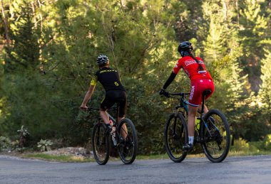 Kemer, Türkiye - 11 Kasım 2021: bisikletçiler dağ ormanlarında asfalt bir yolda seyahat ediyorlar