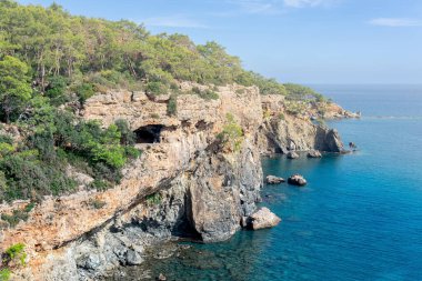 Ormanlık kıyı kayalıkları ve mağarası olan Akdeniz manzarası