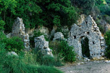 Türkiye 'nin Olimpos kentindeki dağların arka planındaki antik binaların kalıntıları
