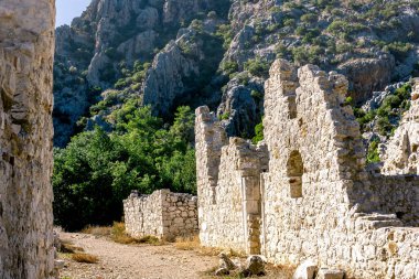 Türkiye 'nin Olimpos kentindeki dağların arkasındaki antik binaların kalıntıları