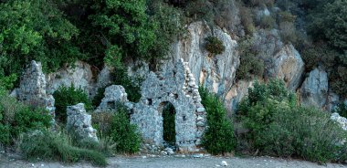 Türkiye 'nin Olimpos kentindeki dağların arka planındaki antik binaların kalıntıları