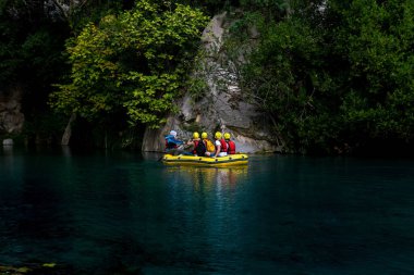 Türkiye 'nin Goynuk kentinde kayalık bir kanyonda mavi suyla yüzen şişme botla turistler