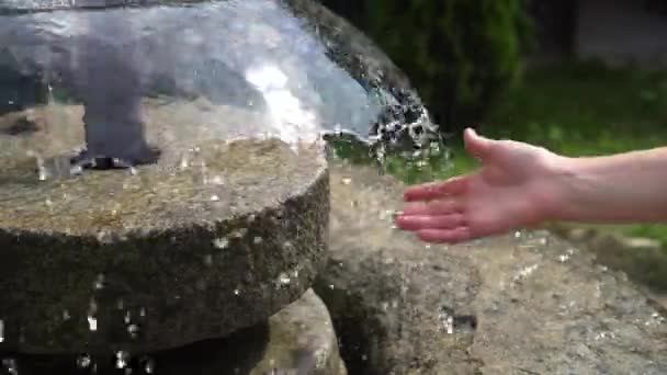 Ένα γυναικείο χέρι στο σπρέι του νερού στο σιντριβάνι — Αρχείο Βίντεο