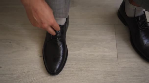 A man ties his shoelaces on black shoes — Stock Video