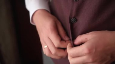 Bir adam takım elbisenin düğmelerini ilikliyor.