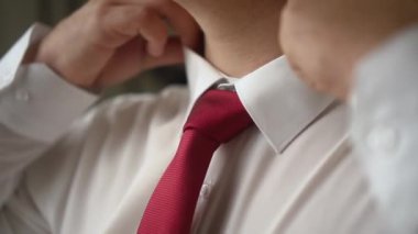 Adam tasmayı ve kravatı ayarlar.