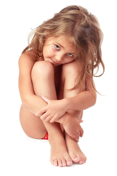 Little girl with matted blond hair sitting and embracing her legs — Stock Photo, Image