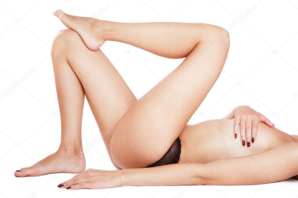 Torso of tanned slim woman with beautiful long legs lying on white background