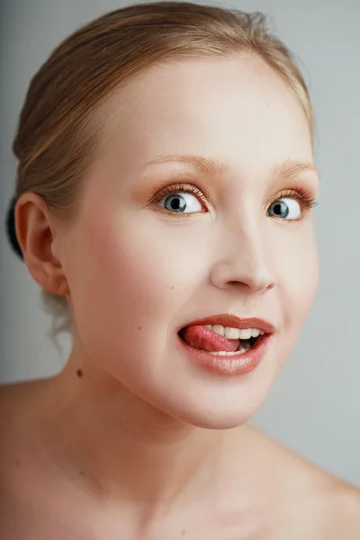 Portrait of pretty young girl with clear professional makeup grimacing and putting out tongue — Stock Photo, Image