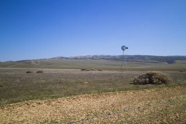 Moinho de vento de campo aberto atrás de arame farpado — Fotografia de Stock
