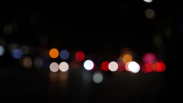 Krásný třpytivý zadek v tmavém rozmazaném pozadí v noci. Kulatý barevný bokeh září ze světel aut na městské ulici. Rozostřená a rozmazaná. Rozostřená světla. Dopravní zácpa. Abstrakt — Stock video