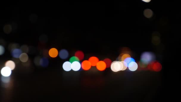 Gecenin karanlığında bulanık arkaplanda güzel, ışıltılı bir bokeh. Şehir caddesindeki araba ışıklarından yuvarlak renkli bokeh parlıyor. Bulanık yüzünden bulanık. Odaklanmamış şehir ışıkları. Trafik sıkışıklığı. Soyut — Stok video