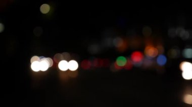 Gecenin karanlığında bulanık arkaplanda güzel, ışıltılı bir bokeh. Şehir caddesindeki araba ışıklarından yuvarlak renkli bokeh parlıyor. Bulanık yüzünden bulanık. Odaklanmamış şehir ışıkları. Trafik sıkışıklığı. Soyut