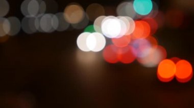 Gecenin karanlığında bulanık arkaplanda güzel, ışıltılı bir bokeh. Şehir caddesindeki araba ışıklarından yuvarlak renkli bokeh parlıyor. Bulanık yüzünden bulanık. Odaklanmamış şehir ışıkları. Trafik sıkışıklığı. Soyut