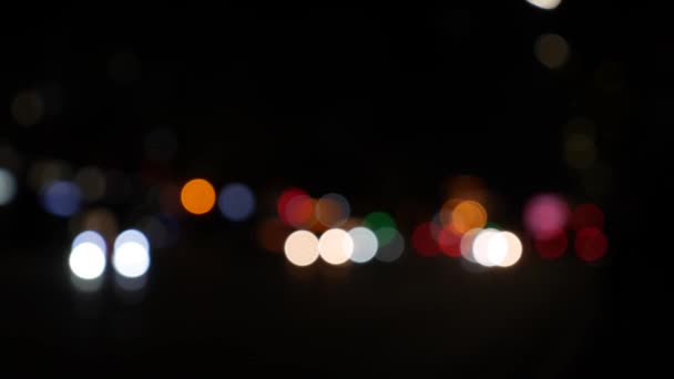 Gecenin karanlığında bulanık arkaplanda güzel, ışıltılı bir bokeh. Şehir caddesindeki araba ışıklarından yuvarlak renkli bokeh parlıyor. Bulanık yüzünden bulanık. Odaklanmamış şehir ışıkları. Trafik sıkışıklığı. Soyut — Stok video