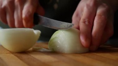 Ev hanımı salata hazırlamak için tahta bir tahtada soğan kesiyor. Soğanlı sebze salatası. Sağlıklı yemek hazırlama kavramı.