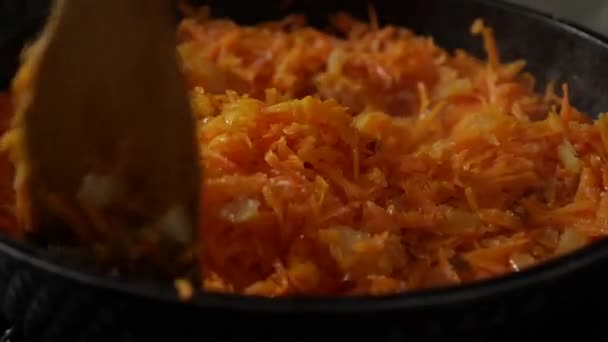 Friggere le cipolle e le carote grattugiate in una padella con olio. Friggere in padella con spatola di legno. — Video Stock