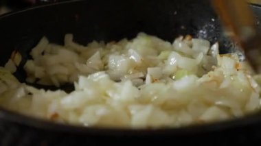Tavada yağlı soğan kızartıyorum. Tavada soğanı ahşap spatulayla karıştır..
