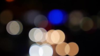 Gecenin karanlığında bulanık arkaplanda güzel, ışıltılı bir bokeh. Şehir caddesindeki araba ışıklarından yuvarlak renkli bokeh parlıyor. Bulanık yüzünden bulanık. Odaklanmamış şehir ışıkları. Trafik sıkışıklığı. Soyut