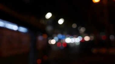 Gecenin karanlığında bulanık arkaplanda güzel, ışıltılı bir bokeh. Şehir caddesindeki araba ışıklarından yuvarlak renkli bokeh parlıyor. Bulanık yüzünden bulanık. Odaklanmamış şehir ışıkları. Trafik sıkışıklığı. Soyut