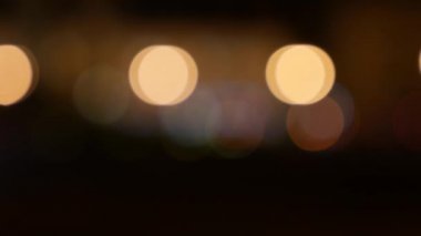 Gecenin karanlığında bulanık arkaplanda güzel, ışıltılı bir bokeh. Şehir caddesindeki araba ışıklarından yuvarlak renkli bokeh parlıyor. Bulanık yüzünden bulanık. Odaklanmamış şehir ışıkları. Trafik sıkışıklığı. Soyut