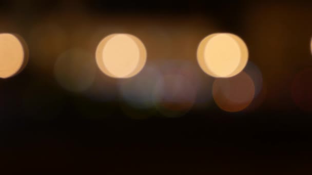 Beautiful glittering bokeh in dark blurry background at night. The round colorful bokeh shine from car lights on city street. Out of focus with blurry. Unfocused city lights. Traffic bokeh. Abstract — Stock Video
