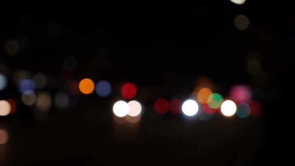Ночью на темном размытом фоне скользит боке. Круглый красочный боке сияет от автомобильных огней на городской улице. Не в фокусе с расплывчатым. Несфокусированные огни города. Пробки на дорогах. Абстрагируясь — стоковое видео