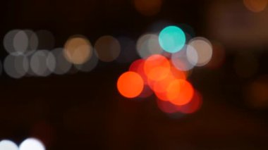 Gecenin karanlığında bulanık arkaplanda güzel, ışıltılı bir bokeh. Şehir caddesindeki araba ışıklarından yuvarlak renkli bokeh parlıyor. Bulanık yüzünden bulanık. Odaklanmamış şehir ışıkları. Trafik sıkışıklığı. Soyut