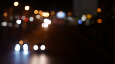 Gecenin karanlığında bulanık arkaplanda güzel, ışıltılı bir bokeh. Şehir caddesindeki araba ışıklarından yuvarlak renkli bokeh parlıyor. Bulanık yüzünden bulanık. Odaklanmamış şehir ışıkları. Trafik sıkışıklığı. Soyut