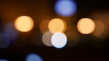 Gecenin karanlığında bulanık arkaplanda güzel, ışıltılı bir bokeh. Şehir caddesindeki araba ışıklarından yuvarlak renkli bokeh parlıyor. Bulanık yüzünden bulanık. Odaklanmamış şehir ışıkları. Trafik sıkışıklığı. Soyut