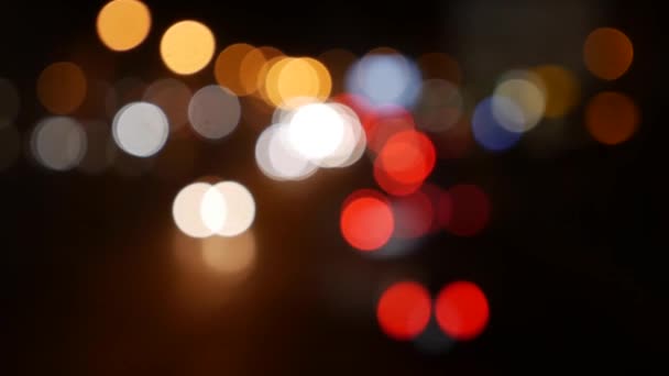Прекрасний блискучий боке в темному розмитому фоні вночі. Круглий барвистий боке світиться від автомобільних вогнів на міській вулиці. За межами фокусу з розмитістю. Неорієнтовані міські вогні. Рухомий боке. Анотація — стокове відео