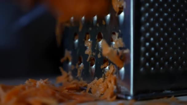 Primo piano di mani di donne grattugia carote su una grattugia. Casalinga griglie carota in cucina. — Video Stock