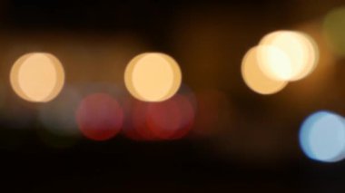 Gecenin karanlığında bulanık arkaplanda güzel, ışıltılı bir bokeh. Şehir caddesindeki araba ışıklarından yuvarlak renkli bokeh parlıyor. Bulanık yüzünden bulanık. Odaklanmamış şehir ışıkları. Trafik sıkışıklığı. Soyut