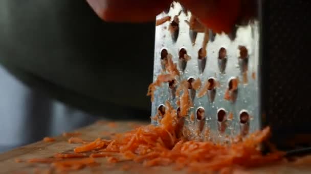 Крупным планом женщины руки решетки морковь на терке. Домохозяйка решетки морковь на кухне. — стоковое видео