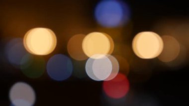 Gecenin karanlığında bulanık arkaplanda güzel, ışıltılı bir bokeh. Şehir caddesindeki araba ışıklarından yuvarlak renkli bokeh parlıyor. Bulanık yüzünden bulanık. Odaklanmamış şehir ışıkları. Trafik sıkışıklığı. Soyut