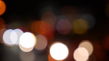 Gecenin karanlığında bulanık arkaplanda güzel, ışıltılı bir bokeh. Şehir caddesindeki araba ışıklarından yuvarlak renkli bokeh parlıyor. Bulanık yüzünden bulanık. Odaklanmamış şehir ışıkları. Trafik sıkışıklığı. Soyut