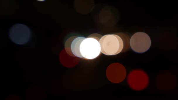 Gecenin karanlığında bulanık arkaplanda güzel, ışıltılı bir bokeh. Şehir caddesindeki araba ışıklarından yuvarlak renkli bokeh parlıyor. Bulanık yüzünden bulanık. Odaklanmamış şehir ışıkları. Trafik sıkışıklığı. Soyut — Stok video