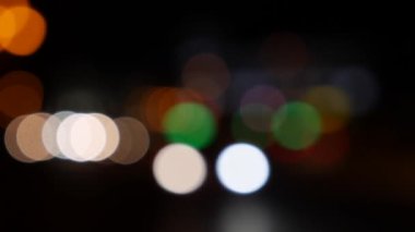 Gecenin karanlığında bulanık arkaplanda güzel, ışıltılı bir bokeh. Şehir caddesindeki araba ışıklarından yuvarlak renkli bokeh parlıyor. Bulanık yüzünden bulanık. Odaklanmamış şehir ışıkları. Trafik sıkışıklığı. Soyut