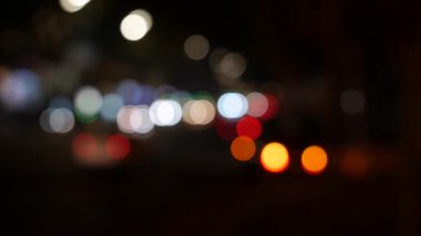 Gecenin karanlığında bulanık arkaplanda güzel, ışıltılı bir bokeh. Şehir caddesindeki araba ışıklarından yuvarlak renkli bokeh parlıyor. Bulanık yüzünden bulanık. Odaklanmamış şehir ışıkları. Trafik sıkışıklığı. Soyut