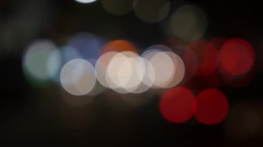 Gecenin karanlığında bulanık arkaplanda güzel, ışıltılı bir bokeh. Şehir caddesindeki araba ışıklarından yuvarlak renkli bokeh parlıyor. Bulanık yüzünden bulanık. Odaklanmamış şehir ışıkları. Trafik sıkışıklığı. Soyut