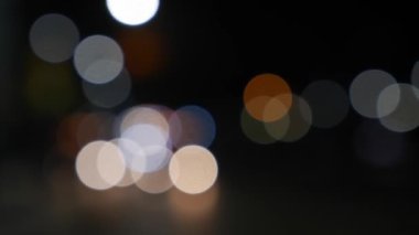 Gecenin karanlığında bulanık arkaplanda güzel, ışıltılı bir bokeh. Şehir caddesindeki araba ışıklarından yuvarlak renkli bokeh parlıyor. Bulanık yüzünden bulanık. Odaklanmamış şehir ışıkları. Trafik sıkışıklığı. Soyut