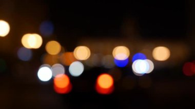 Gecenin karanlığında bulanık arkaplanda güzel, ışıltılı bir bokeh. Şehir caddesindeki araba ışıklarından yuvarlak renkli bokeh parlıyor. Bulanık yüzünden bulanık. Odaklanmamış şehir ışıkları. Trafik sıkışıklığı. Soyut