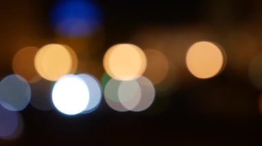 Gecenin karanlığında bulanık arkaplanda güzel, ışıltılı bir bokeh. Şehir caddesindeki araba ışıklarından yuvarlak renkli bokeh parlıyor. Bulanık yüzünden bulanık. Odaklanmamış şehir ışıkları. Trafik sıkışıklığı. Soyut