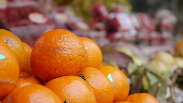 Čerstvé šťavnaté pomeranče na poličce pouličního trhu s potravinami během dne. Zákazníci nakupující čerstvé a organické ovoce. Videoklip