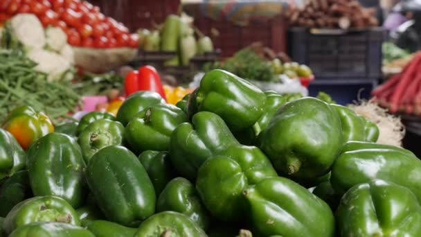 Biologische groene paprika 's en andere groenten te koop op de groentemarkt, close-up. Groenten verkopen in de winkel. Verse peper bij de groenteboer stal. — Stockvideo