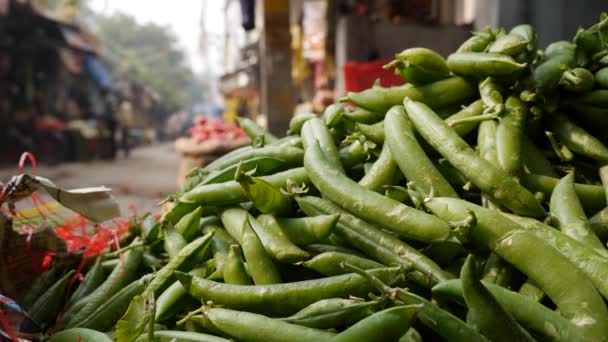野菜市場での販売のためのポッドや他の野菜の緑のエンドウ豆のヒープ。食料品市場で野菜を売る。緑の塊茎の生の緑のエンドウ豆の鞘 — ストック動画