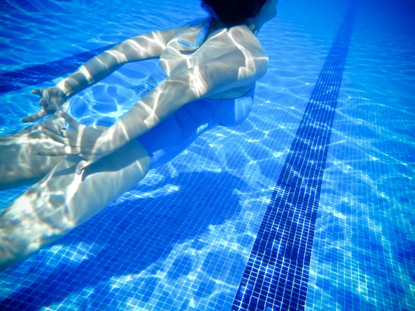Chica nadando bajo el agua en una piscina — Foto de Stock