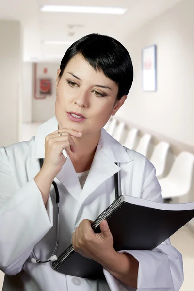 Nachdenkliche brünette Ärztin im Dienst in der Lobby — Stockfoto